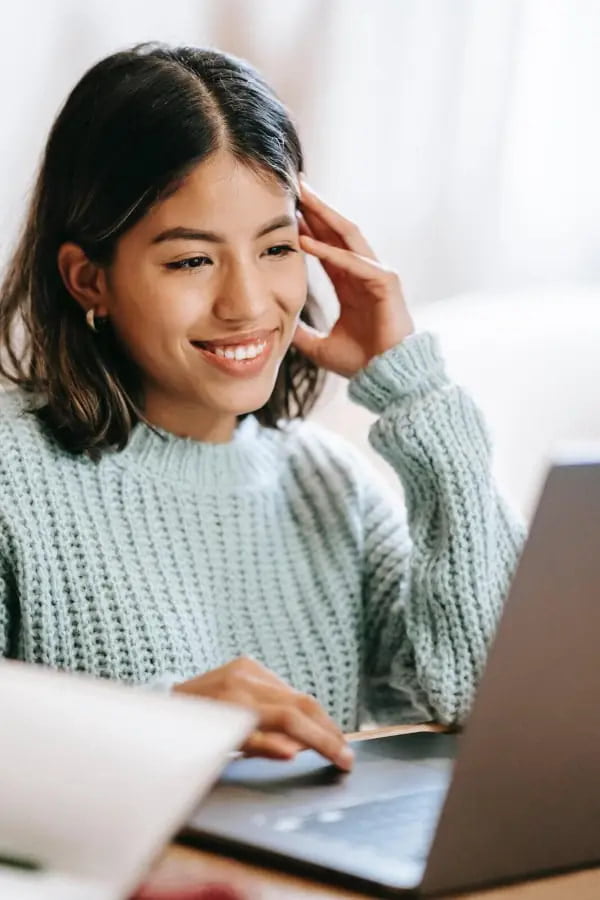hispanic woman in online class on laptop near notepad in apartment
